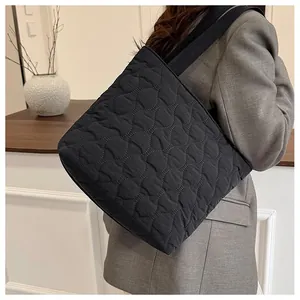 Close-up of a black quilted space cotton tote bag worn by a model in a minimalist setting