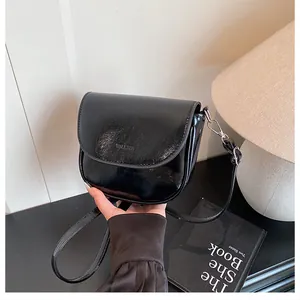 Detail of a black glossy saddle bag featuring sleek leather texture and embossed logo