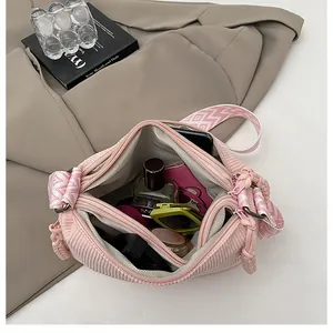 Detalle del interior de la bolsa de pana rosa con compartimentos y correa tejida
