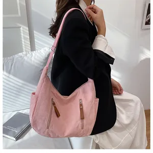 Detail of pink corduroy crossbody bag with double vertical zippers and adjustable strap