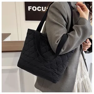 Detailed view of the black wavy quilted nylon tote bag worn by a model in a studio