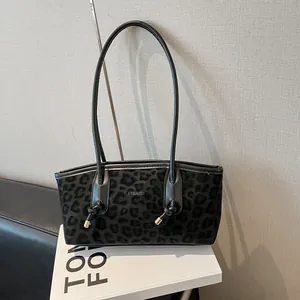 Fashionable black leopard print tote bag with leather strap on a designer book background
