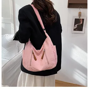 Detail of pink corduroy crossbody bag with adjustable wide strap and decorative zippers