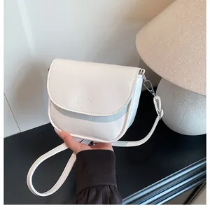 Detailed close-up of a white leather saddle bag with silver metal buckles and logo
