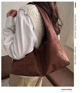 Sac cabas en daim marron montrant sa grande capacité et sa texture douce à l'épaule