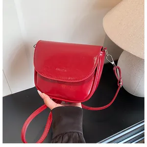 Detail shot of bright red saddle bag with embossed logo and silver metallic hardware hooks
