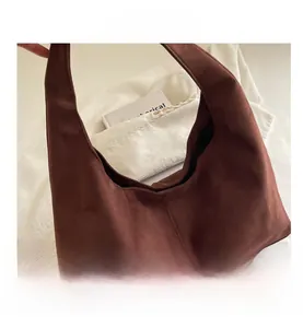 Gros plan sur un sac hobo en daim marron foncé avec coutures verticales et texture