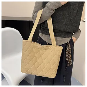Close-up of stylish wavy quilted tote bag in khaki with reinforced shoulder straps