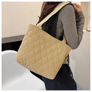 Detailed view of beige quilted tote bag featuring wavy stitching and soft puffer texture