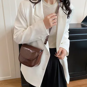 Chic retro brown glossy saddle bag for women shown as a stylish crossbody shoulder purse