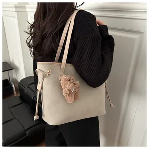 Detail der beigen Shopper-Tasche mit Kordelzug und einem süßen braunen Bären-Anhänger