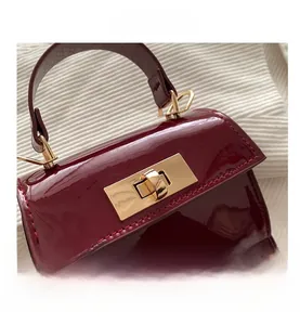 Close-up of burgundy patent leather handbag featuring a gold-toned metal turn-lock closure
