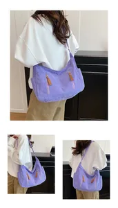 Detail of purple corduroy crossbody bag showing ribbed texture and leather zipper pulls