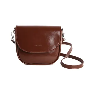 Chic brown patent leather saddle crossbody bag with mirror finish and brand embossing
