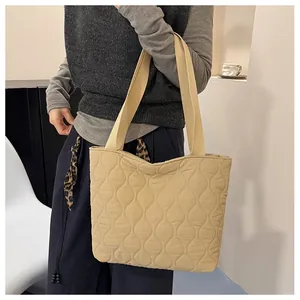 Detail view of khaki quilted puffer tote bag with glossy wave pattern texture