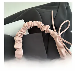 Dettaglio della borsa rosa arricciata con fiocco decorativo e trama effetto velluto