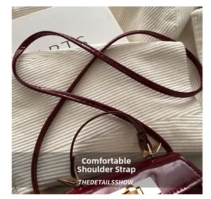 Detail of burgundy patent leather bag with gold buckle and comfortable shoulder straps