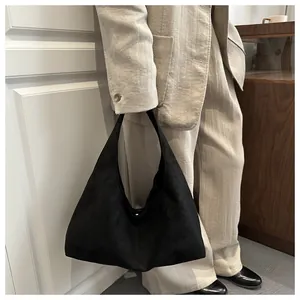 Sac hobo minimaliste en daim noir porté par un mannequin dans un cadre haut de gamme