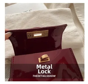 Close-up of golden metal turn-lock on a premium burgundy patent leather handbag