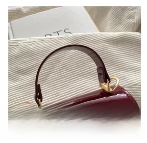 Detail view of wine red patent leather handbag handle and golden metal buckles