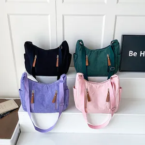 Minimalist corduroy crossbody bags in black, green, purple and pink on a white stand