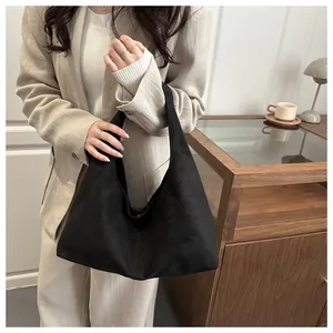 Détail d'un grand sac cabas en daim noir montrant sa texture premium et sa bandoulière robuste