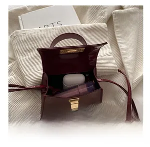 Detail show of wine red patent leather crossbody bag with gold lock and interior space