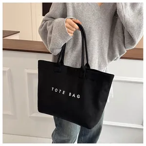 Lifestyle shot of large black suede tote bag with letter print shown on a model