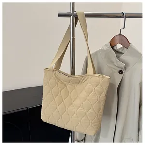 Detail view of wavy quilted texture and fabric strap on beige space cotton tote bag