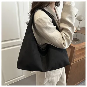 Détail du sac à épaule en daim noir porté par un mannequin pour un look chic au quotidien