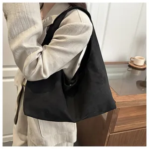 Gros plan d'un sac cabas en daim noir porté par un mannequin dans un bureau moderne