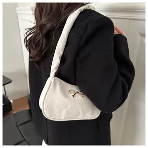 Dettaglio borsa sottobraccio bianco crema con trama marmorea e fiocco dorato chic