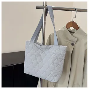 Close-up of light blue quilted tote bag with wave stitching hanging on a coat rack