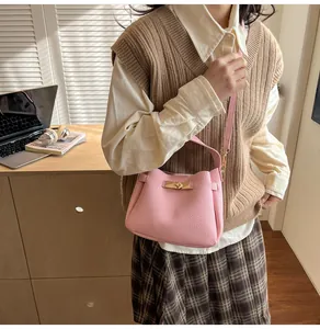 Detailed view of pink lychee grain handbag featuring a golden metallic twist lock closure