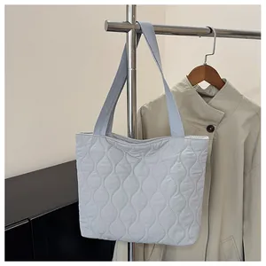 Close-up of a light blue quilted tote bag hanging on a metal rack in a stylish room
