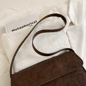 Detail of dark brown retro crossbody bag with textured animal print flap and slim leather strap