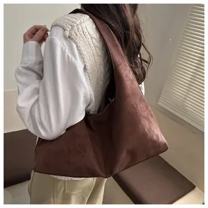 Sac fourre-tout en daim marron porté à l'épaule au design hobo minimaliste et spacieux
