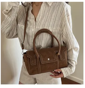 Detail of vintage brown suede handbag with white stitching and detachable shoulder strap