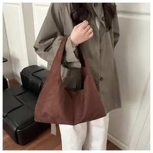 Gros plan d'un grand sac cabas en daim marron foncé avec finition mate tenu par un mannequin
