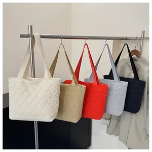 Detailed view of quilted tote bags in five colors with wavy stitching and wide straps