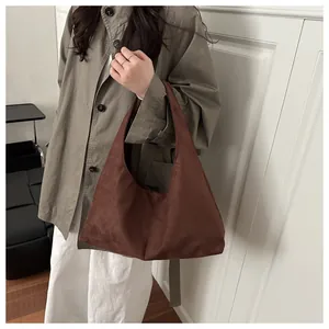 Détail du sac hobo en daim marron foncé porté avec un trench-coat olive chic