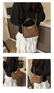 Detail view of brown lychee grain leather bucket bag with gold lock and shoulder strap