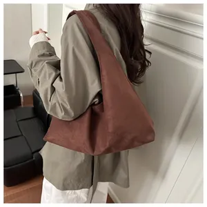 Vue latérale du grand cabas en daim marron foncé montrant sa silhouette hobo minimaliste