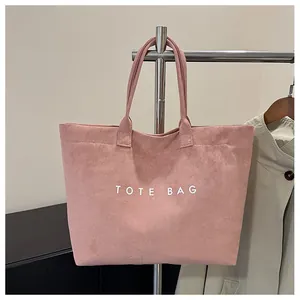 Detailed view of pink suede tote bag with white TOTE BAG text on stainless steel hanger