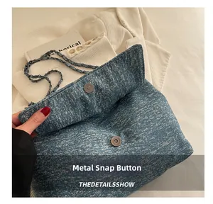 Detail of blue denim tote bag with magnetic snap closure and silver chain strap