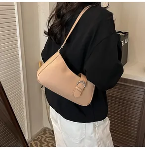 Detailansicht der beigen Hobo-Tasche mit silberner Schnalle, getragen von einem Model