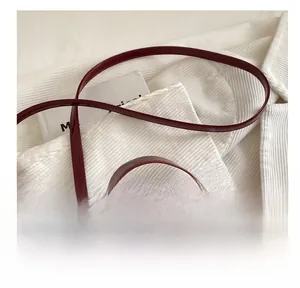 Détail du sac à main bordeaux en cuir croco verni avec breloque cerise et boucle métal