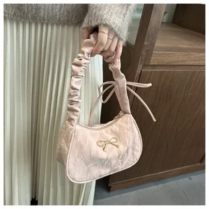Dettaglio del tessuto rosa a fiori e del fiocco dorato sulla borsa con manico a nuvola