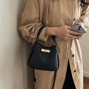 Minimalist black pebble leather bucket bag with gold hardware for crossbody wear