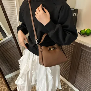 Deep brown pebble leather bucket bag with gold twist lock shown in a cozy lifestyle setting